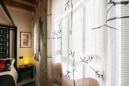 a bedroom with a window with birds on the curtain at Hotel Relais San Nicolò in Treviso