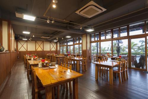 a restaurant with wooden tables and chairs and windows at Kanucha Bay Hotel & Villas in Nago