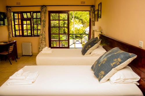 2 Betten in einem Zimmer mit Fenster in der Unterkunft 12 FLEETWOOD in Harare