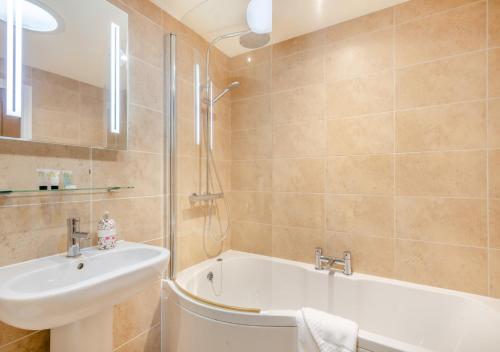 a bathroom with a tub and a sink and a bath tub at Swallows Barn in Little Snoring