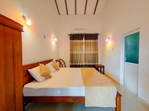 1 dormitorio con cama blanca y almohadas amarillas en Virahi Villa en Wadduwa