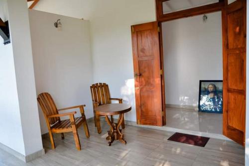 Habitación con 2 sillas, mesa y puerta en Virahi Villa en Wadduwa