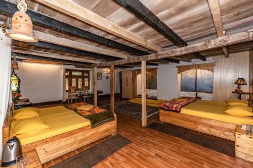 two beds in a room with wooden ceilings at NotOnMap - H2O House in Chamba