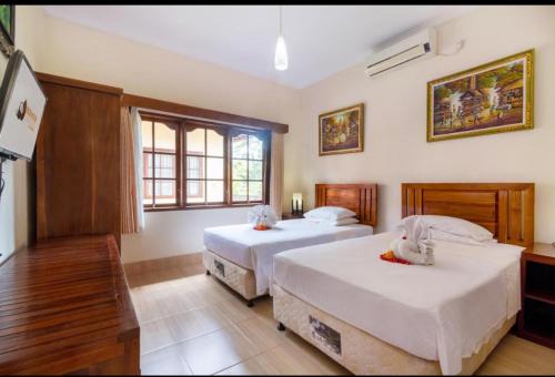 a bedroom with two beds and a window at Bon Nyuh Bungalows in Gianyar