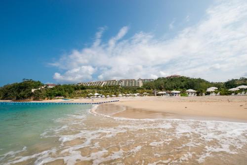 a sandy beach with umbrellas and the ocean at Kanucha Bay Hotel & Villas in Nago