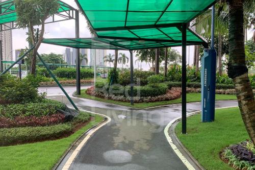 a walkway in a park with palm trees at RedLiving Apartemen Sky House BSD - Lovely Space Tower Leonie in Cilenggang