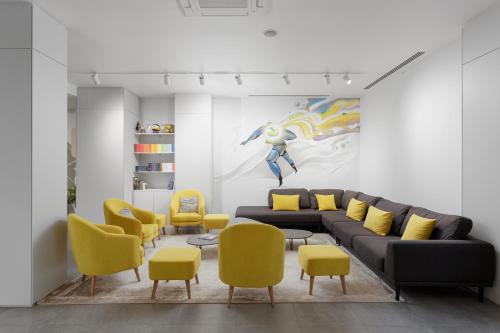 a living room with a couch and yellow chairs at Спорт инн отель и спа in Adler