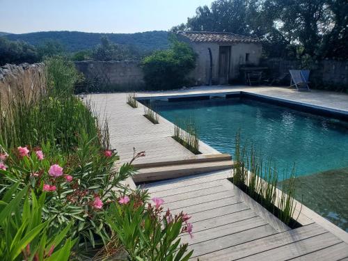 - une piscine avec une passerelle en bois à côté d'une cour dans l'établissement Bergerie des Rêves écogite de groupe, à Puéchabon