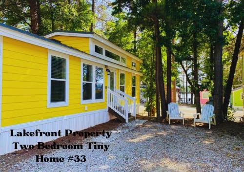 a yellow tiny house with two chairs in front of it at Long Cove Resort and Marina in Charlotte