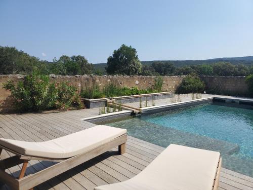 - une piscine sur une terrasse en bois avec 2 chaises dans l'établissement Bergerie des Rêves écogite de groupe, à Puéchabon