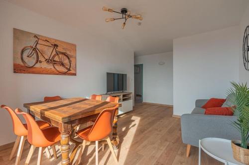 - un salon avec une table en bois et des chaises orange dans l'établissement R'Apparts T4 Les Balcons De Belledonne, à Rhut