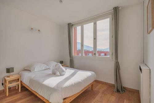 a white bed in a room with a window at R'Apparts T4 Les Balcons De Belledonne in Rhut