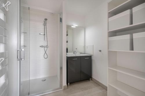 Un baño blanco con ducha y lavabo. en Appartement pour 4 face mer plage + piscine, en La Birochere