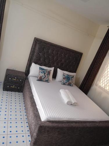 uma cama grande com uma grande cabeceira num quarto em Vilma Apartment em Mombasa