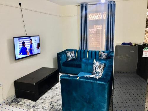 a living room with a blue couch and a tv at Vilma Apartment in Mombasa