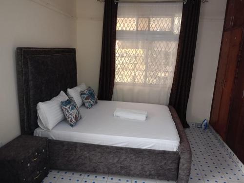 Łóżko w małym pokoju z oknem w obiekcie Vilma Apartment w mieście Mombasa