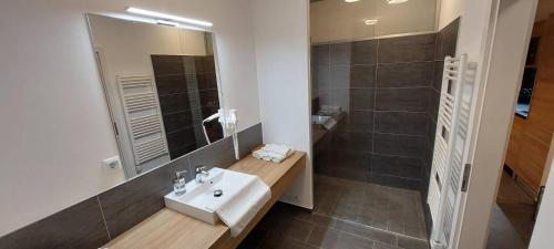 a bathroom with a sink and a mirror and a shower at LUXUS Appartement am Golfplatz und Therme Lutzmannsburg in Zsira