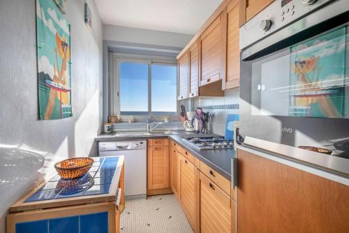 une cuisine avec un évier et une cuisinière four supérieur dans l'établissement Échappée à 4 - Superbe vue mer - 30m de la plage, à La Baule