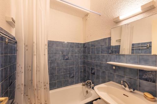 La salle de bains est pourvue de carrelage bleu, d'une baignoire et d'un lavabo. dans l'établissement Le Roc d'Aude - Station Les Angles parking privé, aux Angles