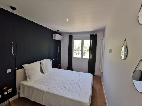 une chambre avec un lit blanc et une fenêtre dans l'établissement Dark blue Appartement 2 chambres climatisation parking 900m des remparts, à Avignon
