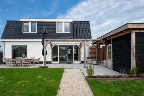 una casa con techo negro y patio en 8 persons waterfront Villa, en Roelofarendsveen