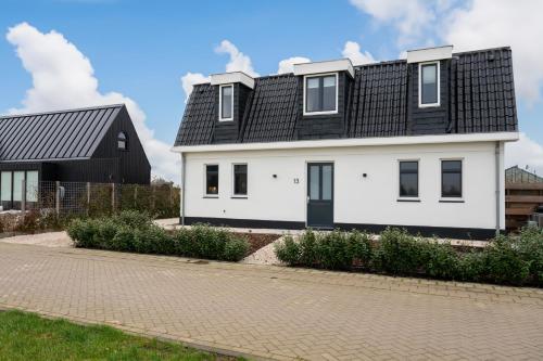 a white house with a black roof at 8 persons waterfront Villa Tulpenacker in Roelofarendsveen