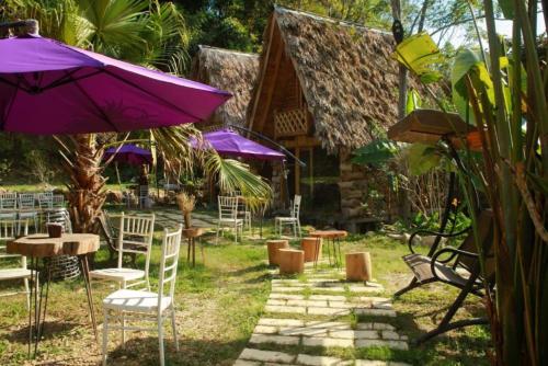 een groep stoelen en tafels met paarse parasols bij Eco Rose Homestay in Diện Biên Phủ