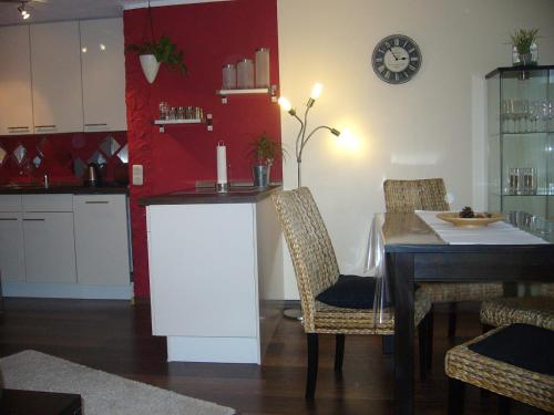 eine Küche und ein Esszimmer mit einem Tisch und einer Uhr in der Unterkunft Voßhörn 27, Ferienwohnung 4 in Cuxhaven