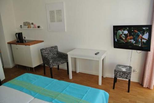 Cette chambre dispose d'une table, d'une télévision et d'un bureau. dans l'établissement Seehütte Ferienwohnung 304, à Cuxhaven