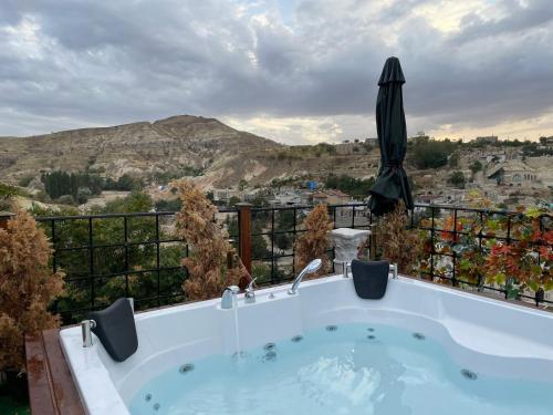 a jacuzzi tub with a umbrella on a balcony at Artium Cave Hotel in Mustafapaşa