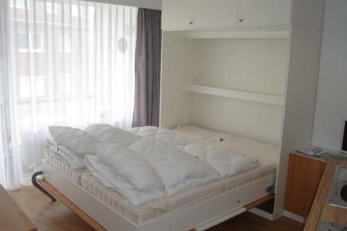 ein weißes Bett in einem Zimmer mit Fenster in der Unterkunft Seehütte Ferienwohnung 104 in Cuxhaven