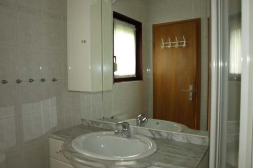 een badkamer met een wastafel, een bad en een spiegel bij Kampweg 18 in Cuxhaven