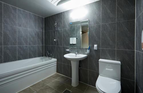 a bathroom with a toilet and a sink and a bath tub at Buantreehotel Blackhouse in Buan