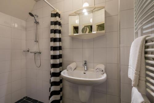 ein weißes Bad mit einem Waschbecken und einer Dusche in der Unterkunft Appartement - Duinweg 117-14 - Zoutelande in Zoutelande