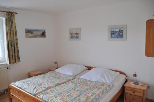 ein Bett in einem Schlafzimmer mit zwei Nachttischen und zwei Bildern in der Unterkunft Nordseedüne, Ferienwohnung 3 in Cuxhaven