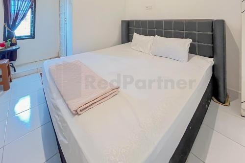 - un lit dans une petite chambre avec une serviette dans l'établissement Namirah Guesthouse Redpartner, à Balikpapan