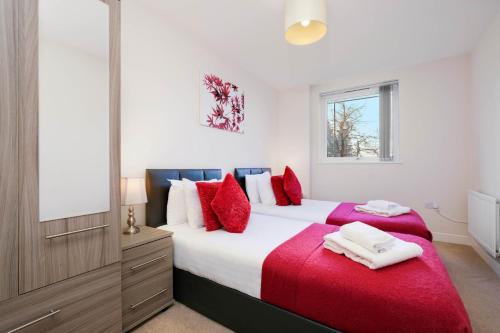 een slaapkamer met een groot bed met rode kussens bij Alder House Serviced Apartment Maidenhead by 360stays in Maidenhead