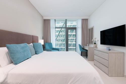 a white bedroom with a large bed and a television at Tamm - Prime Residence with Unrivaled Palm Jumeirah Views in Dubai