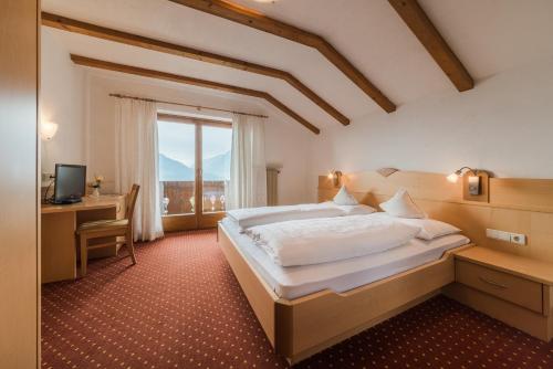 a bedroom with a bed and a desk and a window at Hotel Garni Höfler Fernblick in Schenna