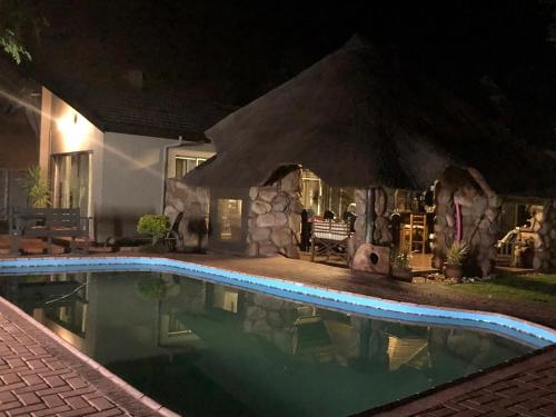 a swimming pool in front of a house at night at Sanyati Guesthouse in Kathu