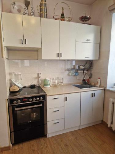 uma cozinha com armários brancos e um fogão preto em One bedroom apartment em Ulan Bator