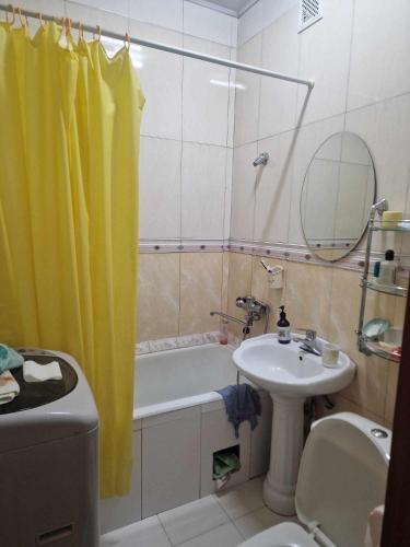 uma casa de banho com uma cortina de chuveiro amarela e um lavatório. em One bedroom apartment em Ulan Bator