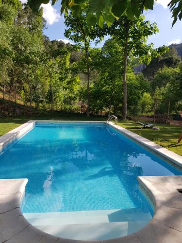 Una piscina con agua azul en un patio. en Alojamientos Rurales Navahondona, en Arroyo Frío