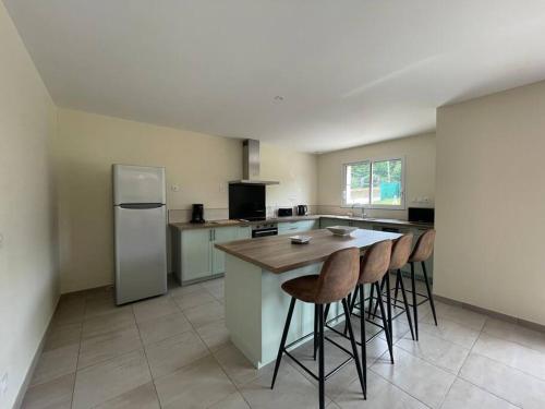 une cuisine avec une table, des chaises et un réfrigérateur dans l'établissement Les Amandiers*Piscine chauffée*3 kms centre historique SARLAT, à Sarlat-la-Canéda
