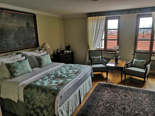 a bedroom with a bed and two chairs and windows at Golden Well in Prague