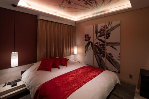 a bedroom with a large bed with red pillows at ホテルCOO玖　男塾ホテルグループ in Okayama