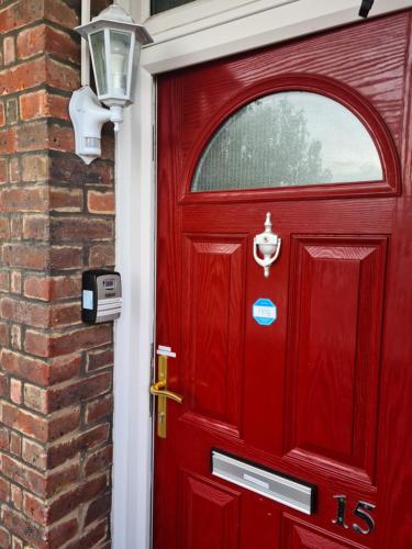 a red door on a brick house with a lamp at Umbrella Properties London Woolwich in London