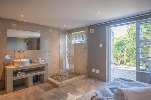 a bathroom with a shower and a sink and a mirror at A Stone's Throw Accommodation in Grahamstown