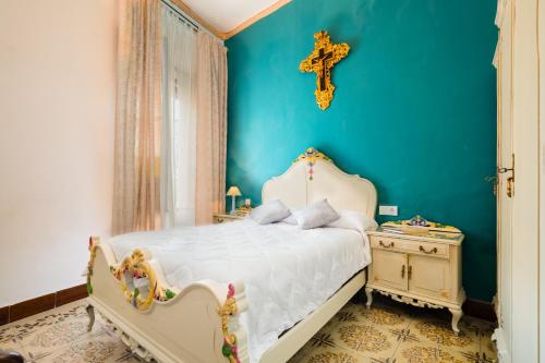 1 dormitorio con 1 cama y 1 cruz en la pared en Una casa azul, en Manzanilla