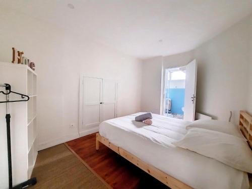 a white bedroom with a bed and a window at LE CARILLOUN in Mirande